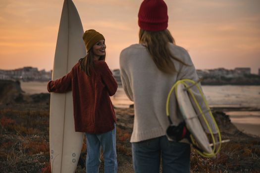 Shot of two female friends holding their surfboards while looking to the ocean