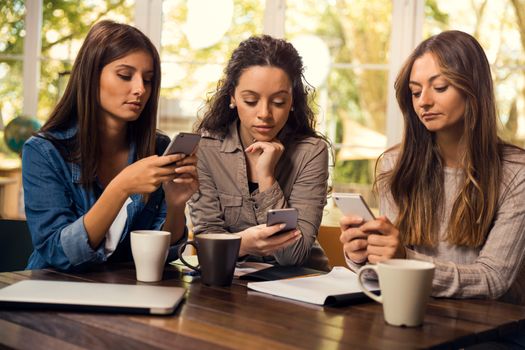 Group of girls with attention on the phone instead of studies