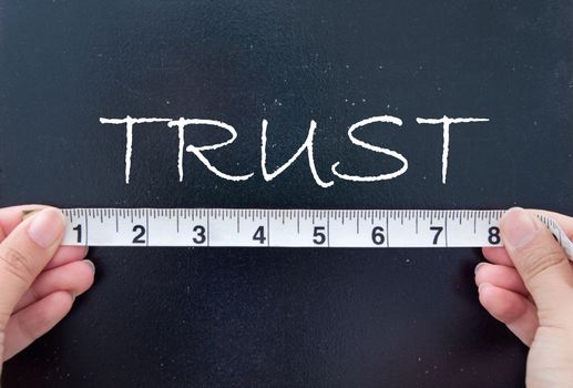 Hands measuring trust on a chalkboard