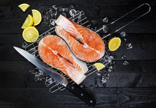 Salmon steaks on ice on black wooden table top view. Fish food concept. Copy space