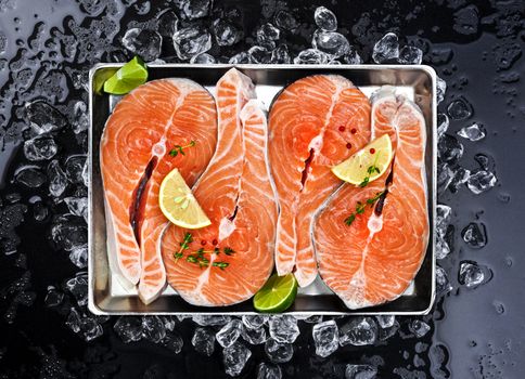 Salmon steaks on ice on black background. Copy space