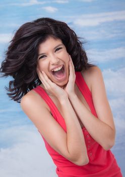 Young beautiful female is screaming or laughing, holding face with hands.