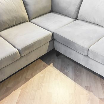 Corner gray velvet sofa on a laminated floor.