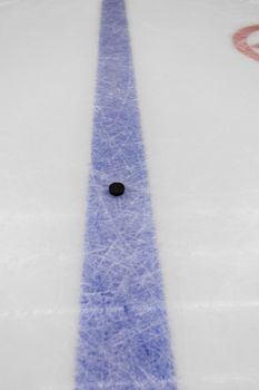 detail blue line with puck on ice hockey rink