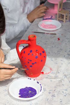 Young children decorating their handmade clay pottery