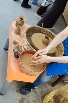 Potter`s hands shaping up the clay of the pot