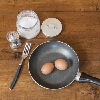 Preparation of fried eggs on a wooden table