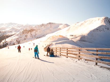 People on ski slope in mountain resort on sunny winter day.