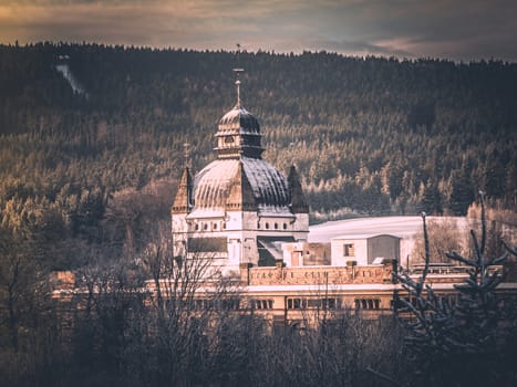 Old mountain factory with ornamental dome in winter landscape. Vintage style image.