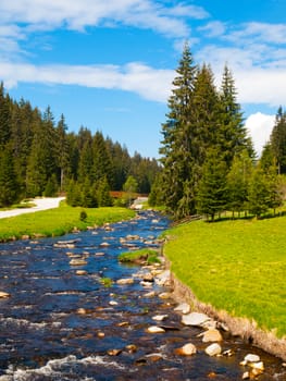 Idyllic landscape with calm mountain river on sunny day. White stones and green meadows and trees. Sumava National Park, Bohemian Forest, Czech Republic.