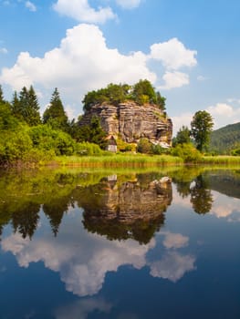 Rock castle Sloup v Cechach reflected in the water on sunny day, Northern Bohemia, Czech Republic