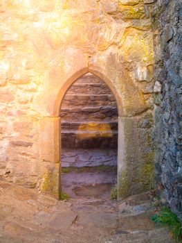 Old gothic arc gate in medieval stone castle ruin.