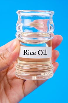 Hand holding Rice oil in a bottle on blue background