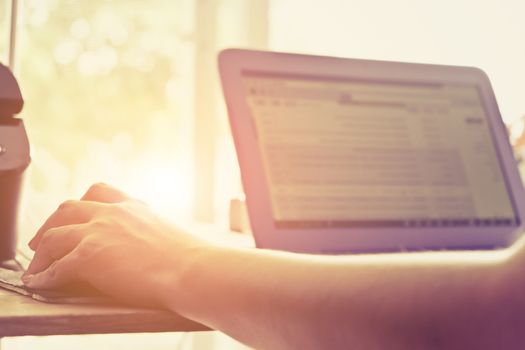 Close-up of female hands using laptop computer, working on laptop with flare light background. Searching Internet ,Businesswoman working at home office
