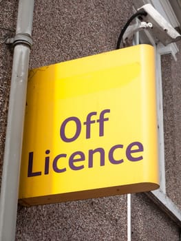 a yellow street and shop sign for the off licence; Essex; UK