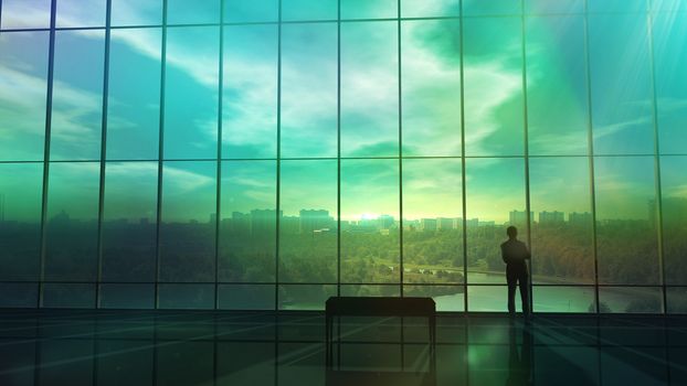 A huge space of empty office building with large windows and only a single silhouette of a man in front of a window.