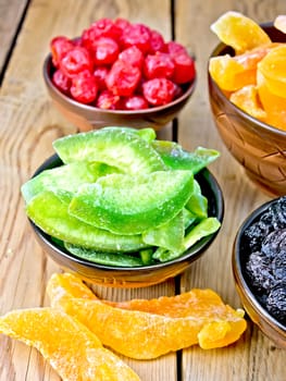 Candied pomelo, cantaloupe, cherries, raisins in bowls on a wooden boards background