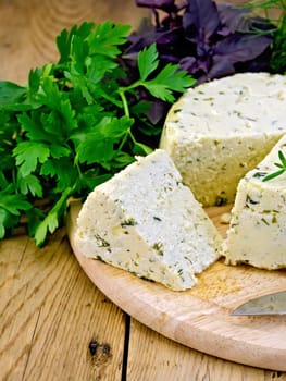 Homemade round cheese with herbs and spices, parsley, basil, dill, tarragon and rosemary on a wooden boards background