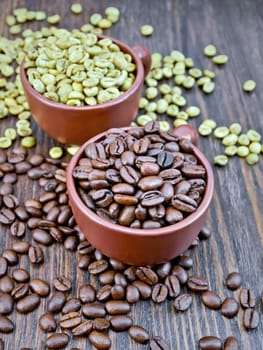 Grains of green and black coffee in brown clay cups and on a table on the background of a wooden board