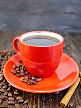 Coffee in red cup with cinnamon on a background of wooden boards