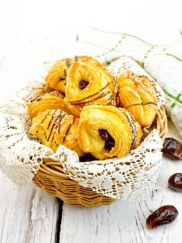 Cookies with dates in a wicker basket with a napkin, fruit and towel on a background of wooden boards