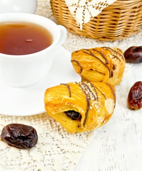 Cookies with dates, tea in a white cup on a napkin against the background of wooden boards
