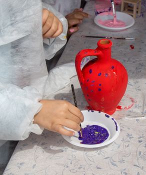 Young children decorating their handmade clay pottery