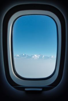 Airplane passenger window with a view on the Himalayas during a flight from Kathmandu to Pokhara in Nepal