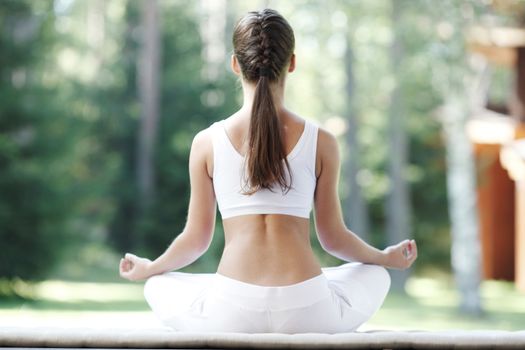 Pretty young woman doing yoga exercise in the park