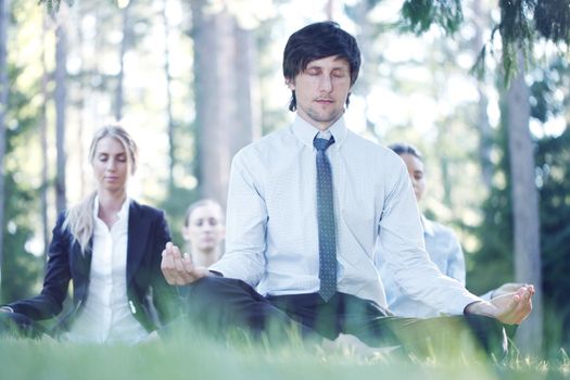 Business people practicing yoga in park