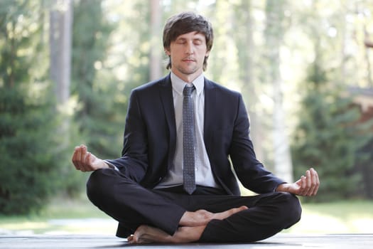 Businessman in suit practicing yoga in park