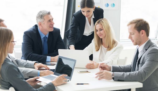 Business person group in formalwear discuss documents at meeting in modern office