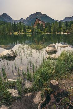 Strbske Pleso Mountain Lake in High Tatras Mountains, Slovakia with Rocks, Stump and Grass in Foreground in the Rain