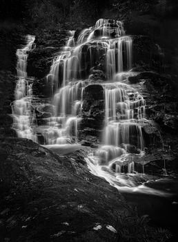 Cascading waterfalls flow over and down rocks as they make their way to the valley floor.  Location - Sylvia Falls, Wentworth Falls Blue Mountains Australia