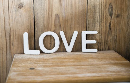 white letters making the word love on wooden bedside table in bedroom