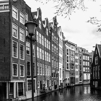 Typical water canal - gracht - and narrow houses along it in Amsterdam city centre, Netherlands, black and white image