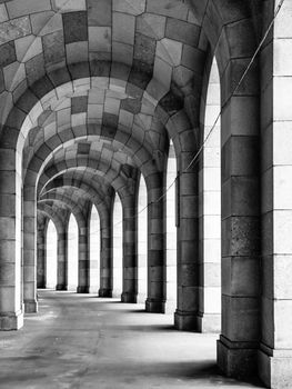 Old arched stone colonnade curved to the left. Black and white image.