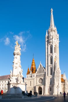 Roman Catholic Matthias Church and Holy Trinity plaque column at Fisherman's Bastion in Buda Castle District, Budapest, Hungary, Europe. Sunny day shot with clear blue sky.