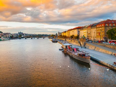 Evening view of Rasin Embankment with boats on Vltava River in Prague, Czech Republic