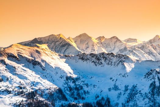 Winter snowy peaks of Alps. Mountain panorama illuminated by sunset at evening time. Austria and Switzerland, Europe.