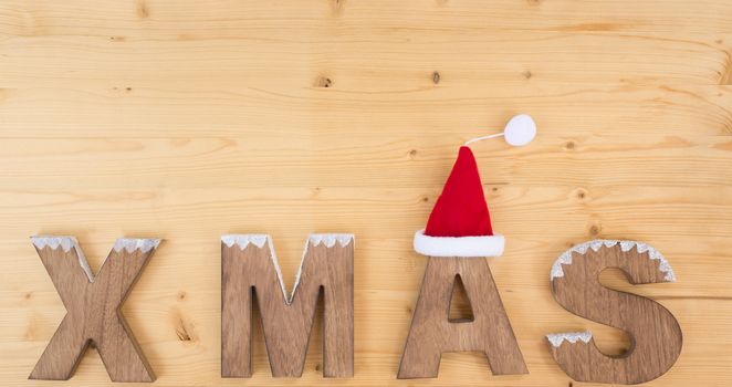 The word X MAS made on wood on wood and santa claus hat