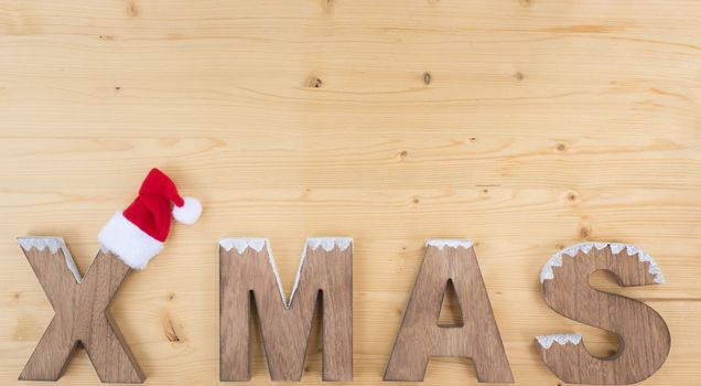 The word X MAS made on wood on wood and santa claus hat