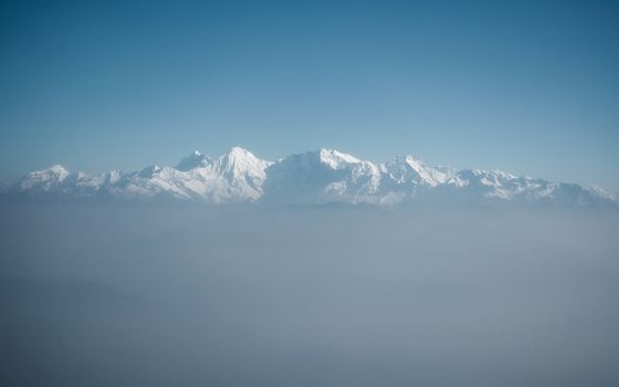 The Himalayas as seen from an airplane in Nepal. Layer of clouds beneath the mountain tops.
