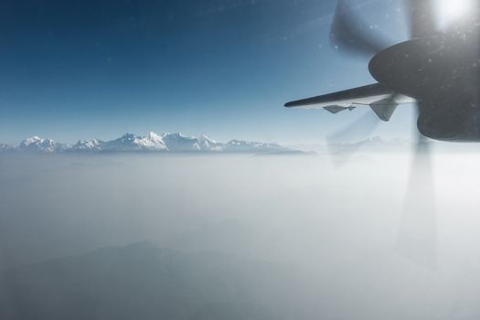 The Himalayas as seen from a propeller plane in Nepal. Layer of clouds beneath the mountain tops.