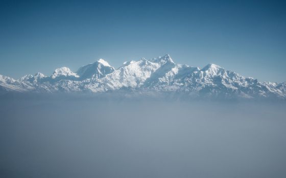 The Himalayas as seen from an airplane in Nepal. Layer of clouds beneath the mountain tops.