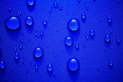 Close up Water drops pattern over a blue waterproof cloth background. World Water Day concept.