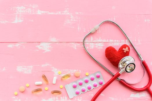 World health day, Healthcare and medical concept. Red heart with Stethoscope, notepad, thermometer and yellow Pill on Pastel white and pink wooden background.