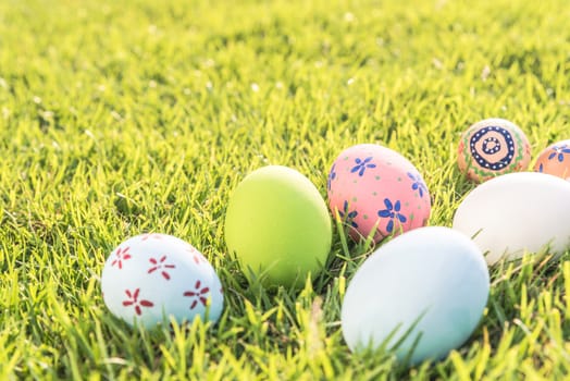 Happy easter!  Closeup Colorful Easter eggs on green grass field during sunset background.