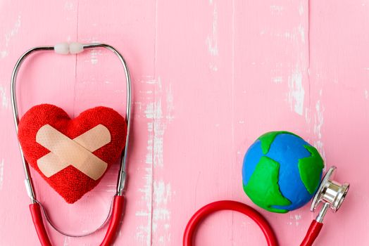 World health day, Healthcare and medical concept. Red heart with Stethoscope, handmade globe, thermometer and yellow Pill on Pastel white and pink wooden background.