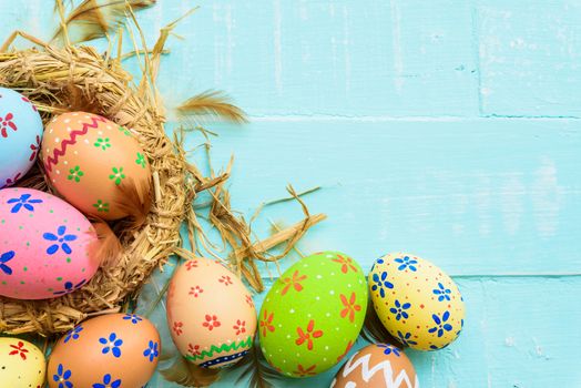 Happy easter! Colorful of Easter eggs in nest on pastel color bright green and white wooden background.